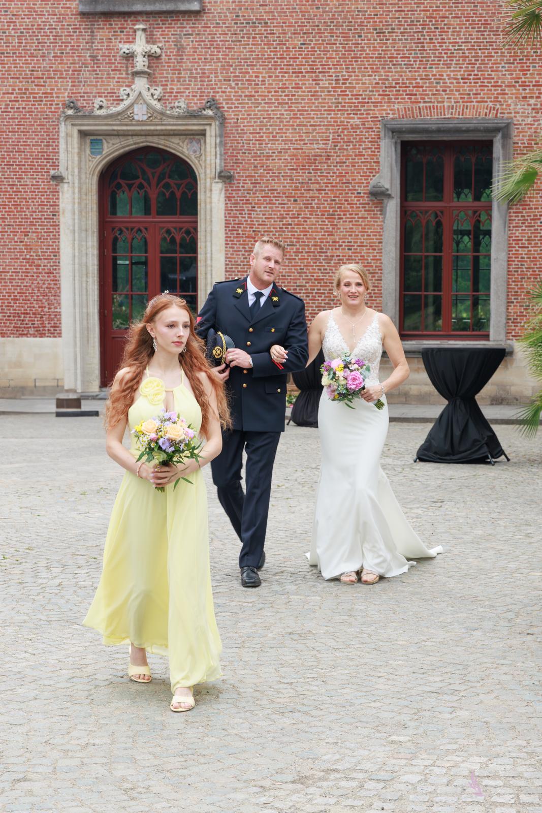 La mariée escortée par son fils en tenue de sapeur-pompier, précédée par sa fille